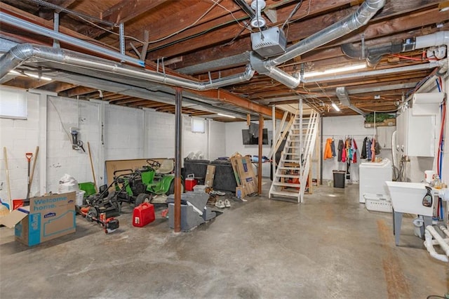 unfinished below grade area featuring washer / dryer, stairway, concrete block wall, and a sink