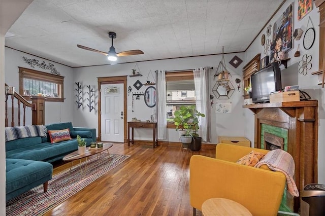living area featuring wood-type flooring, ceiling fan, and a fireplace