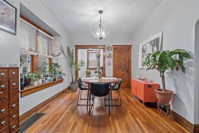 dining area featuring wood-type flooring, a chandelier, and baseboards