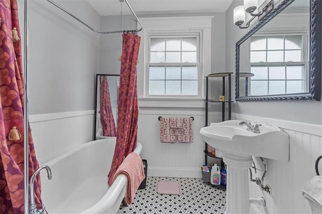full bath featuring wainscoting, a tub to relax in, and plenty of natural light