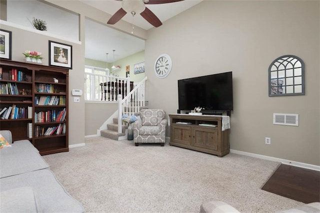living room with stairway, a ceiling fan, carpet, and baseboards