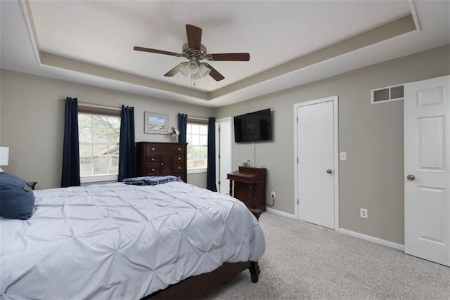 carpeted bedroom with a raised ceiling, baseboards, and a ceiling fan