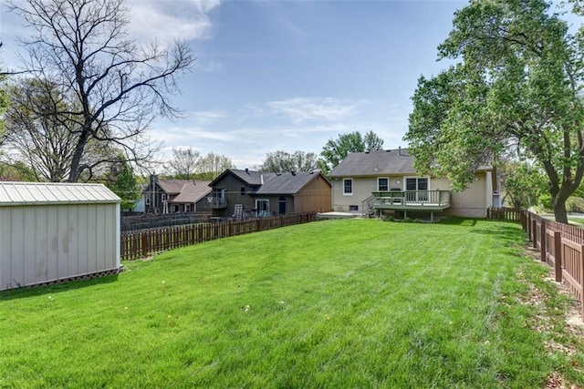 view of yard featuring an outdoor structure, a wooden deck, a storage shed, and a residential view