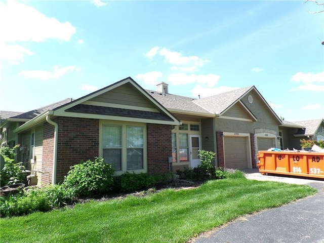 single story home with brick siding, an attached garage, a chimney, and a front yard
