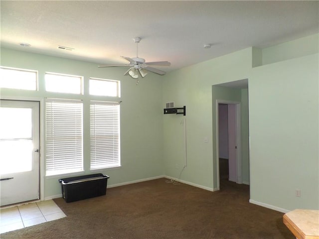 carpeted empty room with baseboards, a ceiling fan, and visible vents