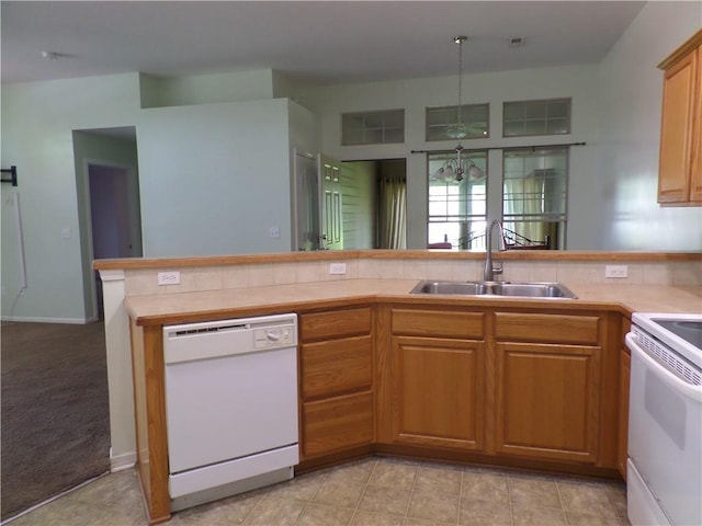 kitchen with brown cabinetry, a peninsula, white appliances, light countertops, and a sink