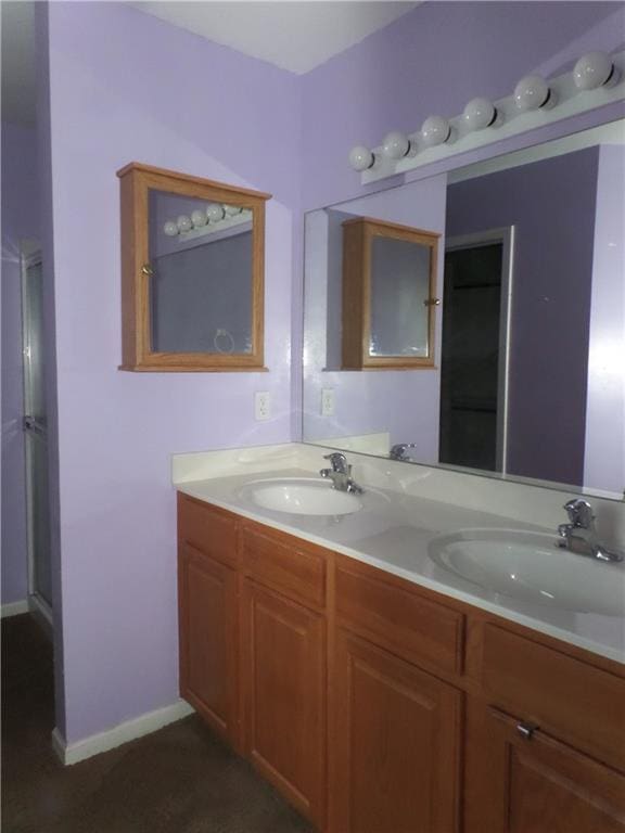 full bath with a sink, baseboards, and double vanity