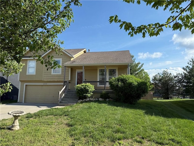 tri-level home with covered porch, a front yard, driveway, and a garage