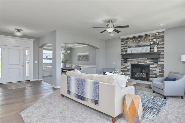 living room featuring arched walkways, ceiling fan with notable chandelier, and a fireplace