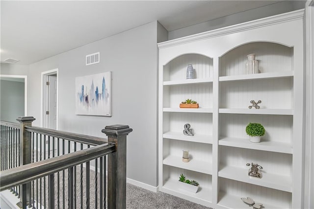 hall featuring baseboards, visible vents, carpet, and an upstairs landing