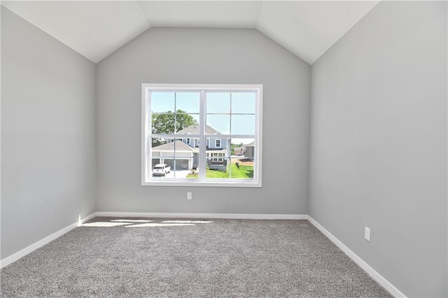 spare room featuring vaulted ceiling, baseboards, and carpet flooring