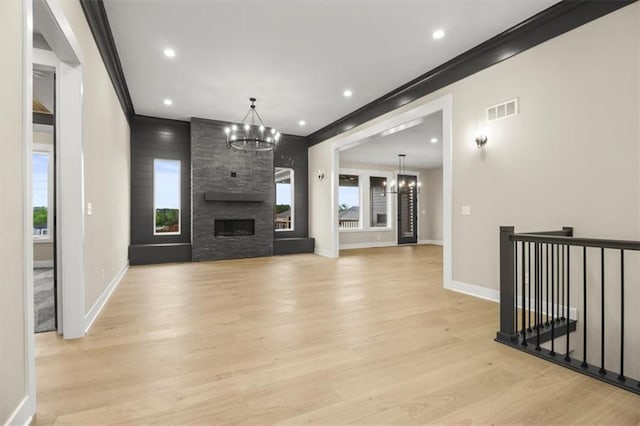 2608 NE Amanda Ln, Blue Springs, MO 64029 - unfurnished living room featuring a chandelier, crown molding, light wood-type flooring, recessed lighting, and a fireplace