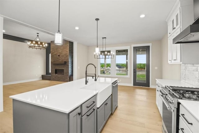 2608 NE Amanda Ln, Blue Springs, MO 64029 - kitchen with exhaust hood, a chandelier, a large fireplace, stainless steel appliances, and recessed lighting