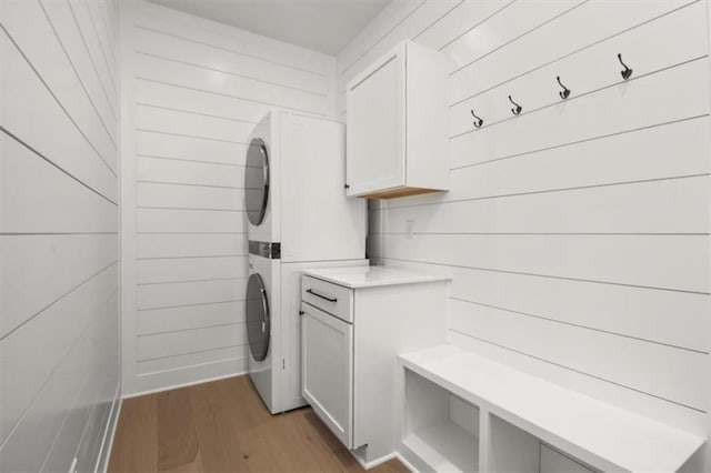 2608 NE Amanda Ln, Blue Springs, MO 64029 - laundry room featuring stacked washer / dryer, light wood-style flooring, cabinet space, and wooden walls