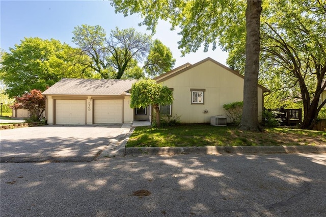 view of front of property with an attached garage, driveway, and central air condition unit