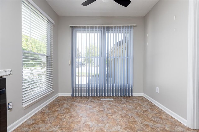 spare room featuring stone finish floors, ceiling fan, and baseboards