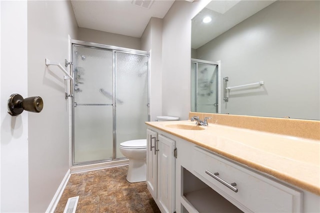 bathroom featuring toilet, baseboards, a stall shower, stone finish flooring, and vanity