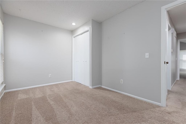 carpeted empty room with a textured ceiling, baseboards, and recessed lighting