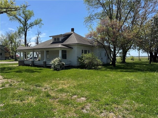 318 S Williams St, Craig, MO 64437 - view of home's exterior featuring a porch, a lawn, and a chimney