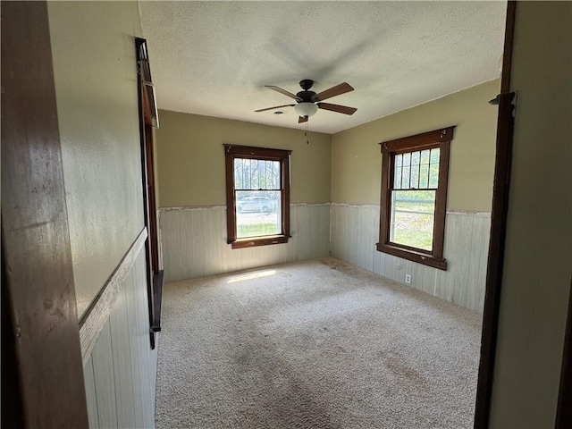 318 S Williams St, Craig, MO 64437 - spare room featuring a wainscoted wall, a ceiling fan, carpet flooring, and a textured ceiling
