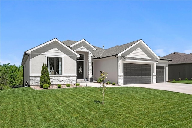 view of front of property featuring stone siding, an attached garage, driveway, and a front yard