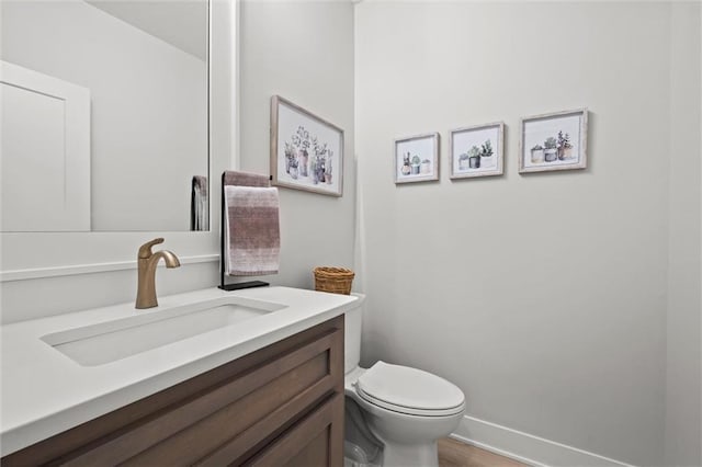 half bath with vanity, toilet, and baseboards