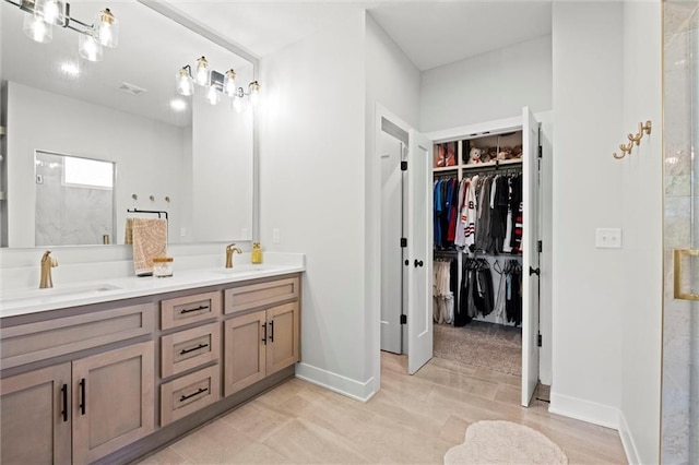 bathroom featuring double vanity, a spacious closet, baseboards, and a shower