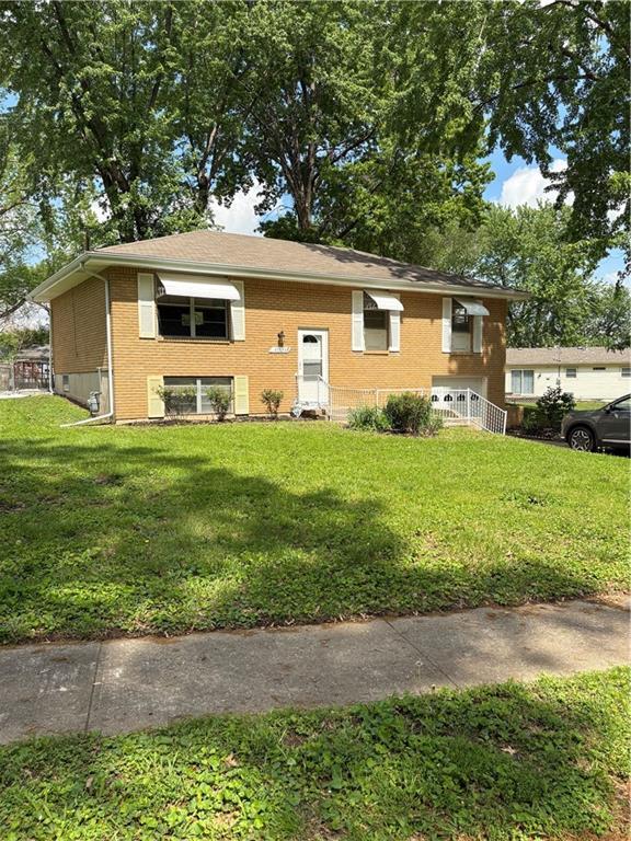raised ranch with brick siding and a front yard