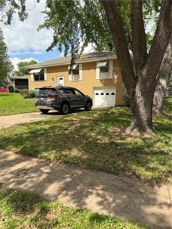 view of front of house with a garage, a front yard, driveway, and brick siding