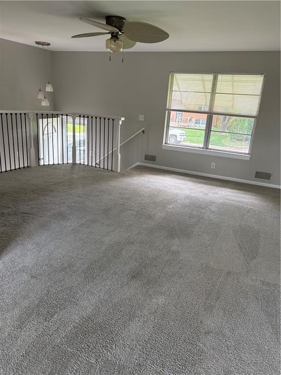 empty room with ceiling fan, visible vents, and carpet
