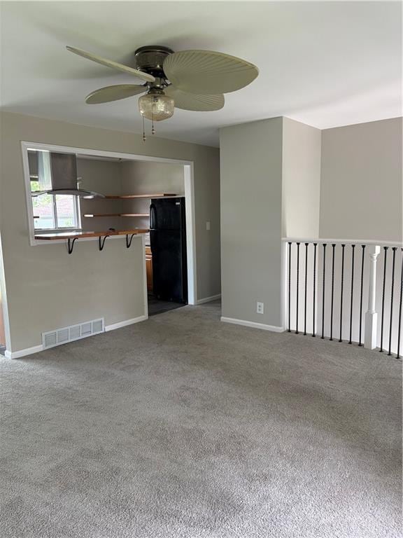 unfurnished living room with carpet floors, a ceiling fan, baseboards, and visible vents
