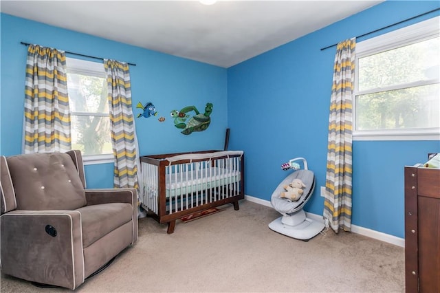 carpeted bedroom featuring baseboards, multiple windows, and a crib