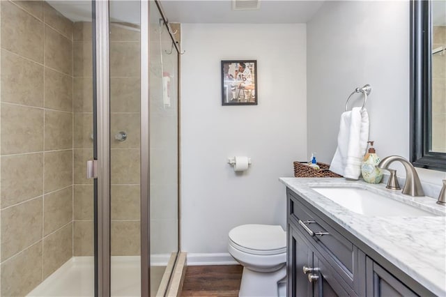 full bath featuring vanity, a stall shower, toilet, and wood finished floors