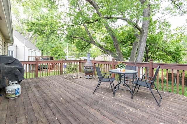 wooden deck featuring outdoor dining area and a grill