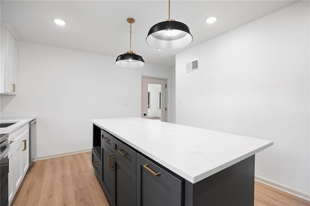 1639 Indiana St, Lawrence, KS 66044 - kitchen featuring white cabinets, light wood-style floors, light countertops, a kitchen island, and recessed lighting