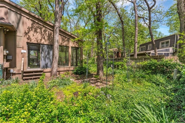 view of yard with fence, a sunroom, and entry steps