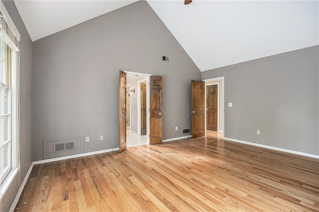 unfurnished bedroom featuring high vaulted ceiling, light wood-style floors, baseboards, and multiple windows