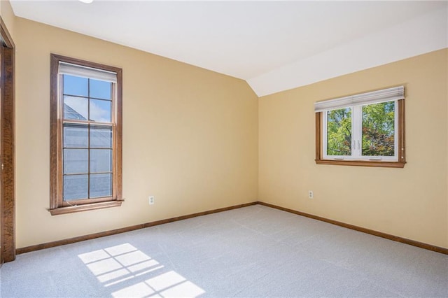 unfurnished room with light colored carpet, baseboards, and vaulted ceiling