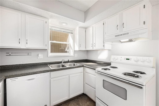 kitchen with a sink, dark countertops, under cabinet range hood, and white appliances