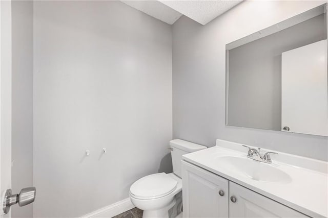 bathroom featuring baseboards, vanity, toilet, and a textured ceiling
