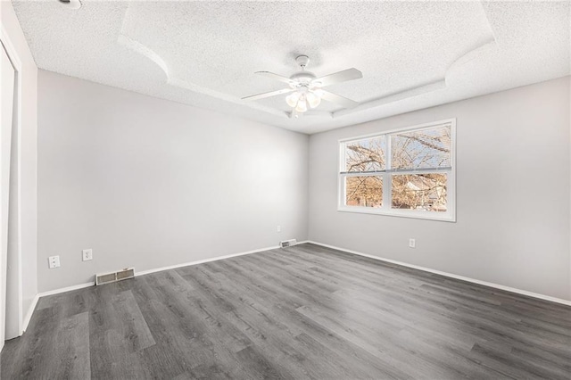unfurnished room featuring a ceiling fan, a textured ceiling, visible vents, and dark wood-type flooring