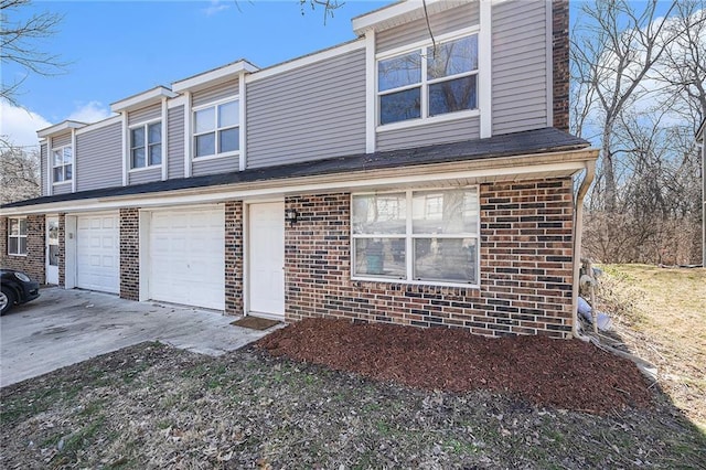 traditional-style house with an attached garage, concrete driveway, and brick siding