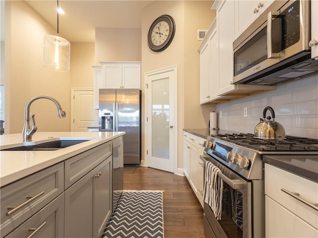 6529 Barth Rd, Shawnee, KS 66226 - kitchen with stainless steel appliances, a sink, decorative backsplash, dark wood-style flooring, and pendant lighting