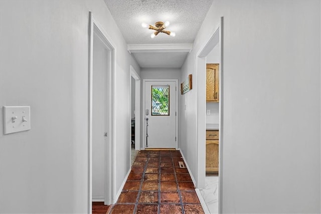 doorway with a textured ceiling and baseboards
