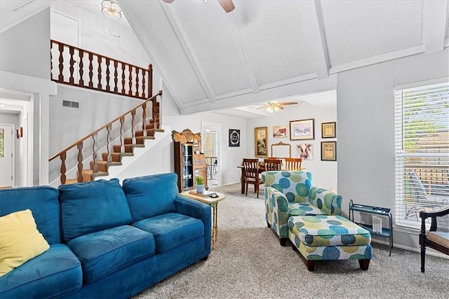 carpeted living room with a ceiling fan, high vaulted ceiling, beam ceiling, and stairway