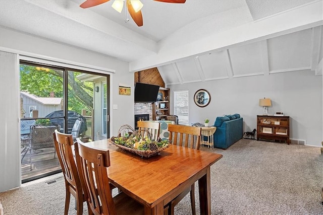 carpeted dining area with a ceiling fan and a large fireplace