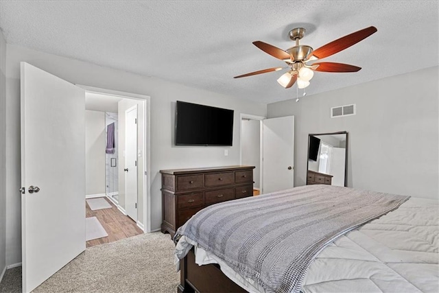 bedroom featuring carpet, baseboards, a textured ceiling, connected bathroom, and a ceiling fan