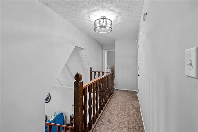 hall with a textured ceiling, carpet floors, and a chandelier