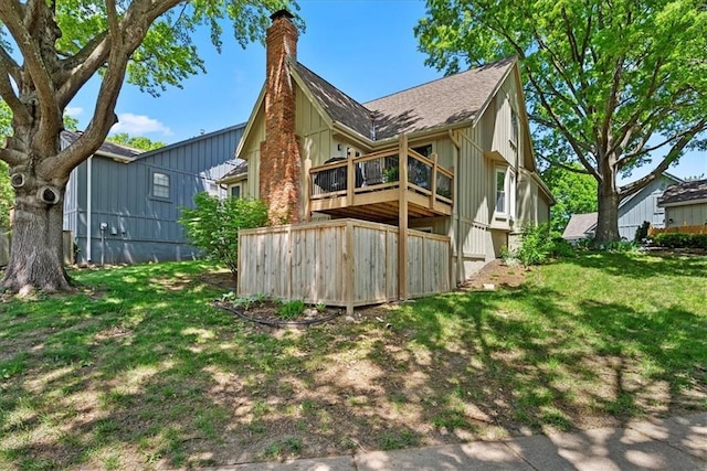 back of property with a chimney, a lawn, and a shingled roof