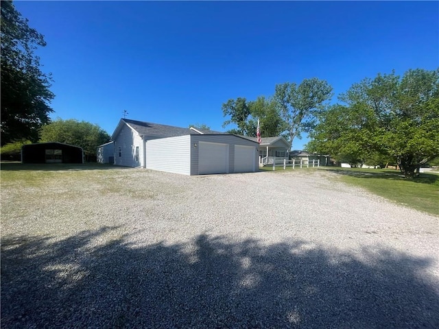 view of property exterior featuring a detached carport, an outbuilding, driveway, and an attached garage